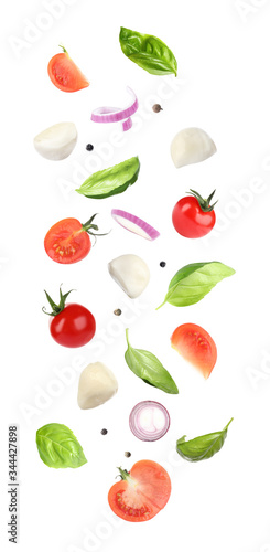 Fototapeta Naklejka Na Ścianę i Meble -  Mozzarella cheese, tomatoes, onion and basil leaves falling on white background
