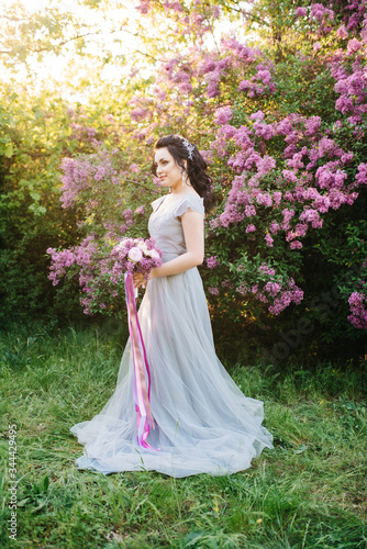 portrait of a brunette girl in a lilac spring garden