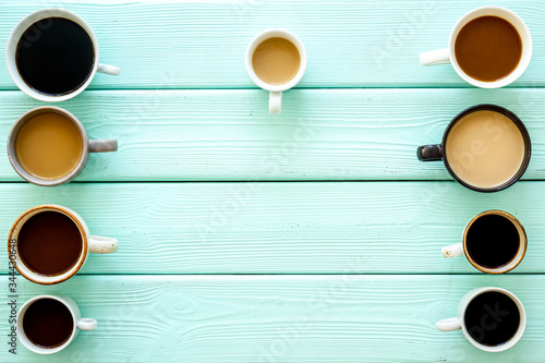 Cups of hot drinks on green wooden background from above frame copy space photo