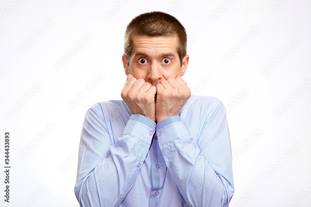 timid shy hesitant man pressed his fists to his lips, head, in a blue light casual shirt. Isolated timid shy hesitant man pressed his fists to his lips, head, in a blue light casual shirt. Isolated