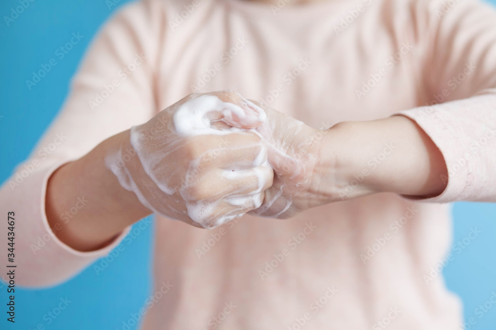 Child girl washes hands with soap on a blue background. Hand disinfection. Epidemic Covid-19. Child girl washes hands with soap on a blue background. Hand disinfection. Epidemic Covid-19.