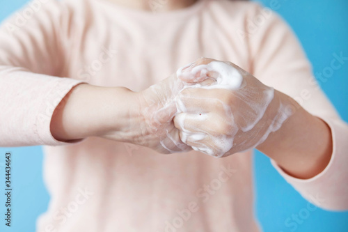 Child girl washing hands with soap on a blue background. Hand disinfection. Epidemic Covid-19.
