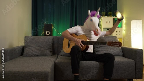the man in the mask of a unicorn playing the guitar and dancing to the music