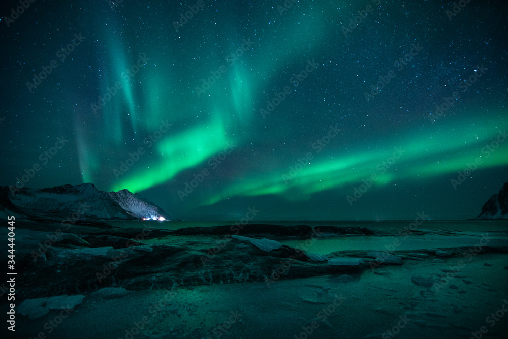 Naklejka premium polar lights also called northern lights or aurora borealis in northern norway during winter above a fjord and snow covered mountains