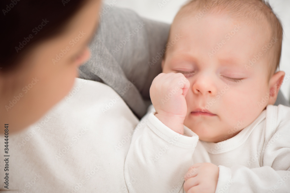 Young mother holding her newborn child. Mom nursing baby. Woman and new born boy relax in a white bedroom. Young mother holding her newborn child. Mom nursing baby. Woman and new born boy relax in a white bedroom.