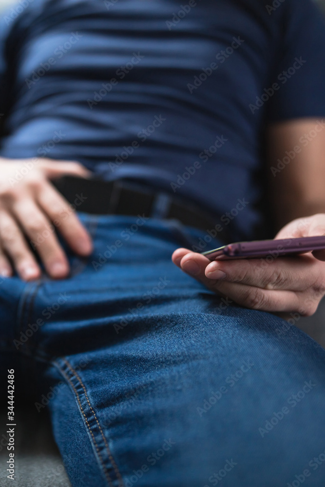 Man holding modern smartphone / cellphone and watching XX videos on a home couch. Taboo still in modern times. Man holding modern smartphone / cellphone and watching XX videos on a home couch. Taboo still in modern times.