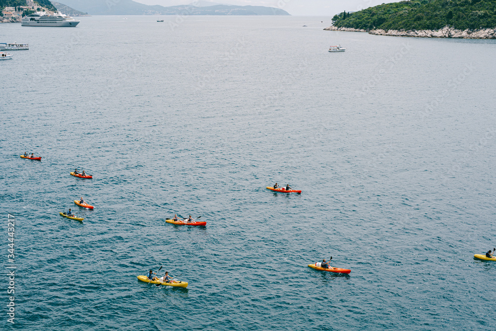 A group of tourists travel in pairs kayaks by sea, near old town of Dubrovnik, Croatia. Concept banner travel. Aerial top view.