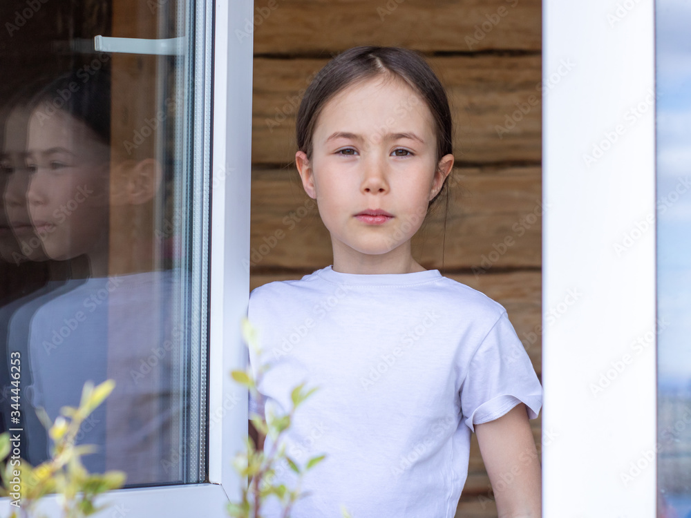 Φωτογραφία Child girl looks out the window of her apartment and enjoys the spring sun
