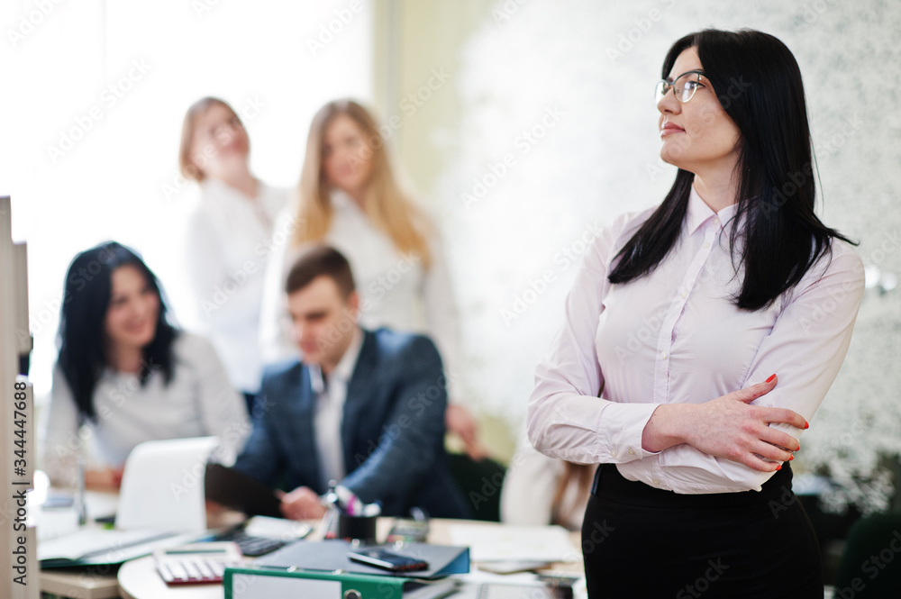 Portrait of caucasian woman in white blouse and eyeglasses against business people group of bank workers have meeting and working in modern office. Portrait of caucasian woman in white blouse and eyeglasses against business people group of bank workers have meeting and working in modern office.