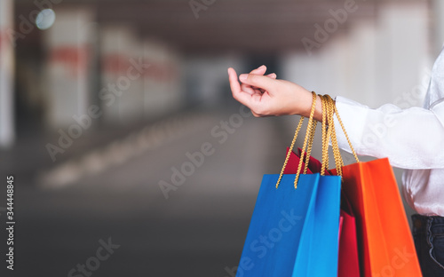 Closeup image of a woman's arm holding shopping bags in the mall parking lot