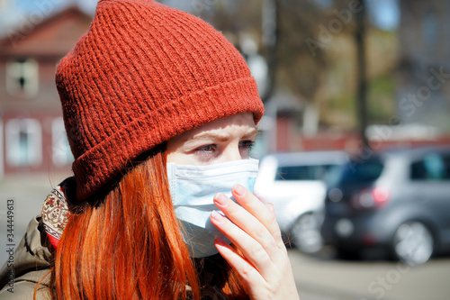 OLYMPUS DIGITBeautiful young European woman with ginger coloured hair on the street with a medical face mask on. Closeup of a young female in a respirator to protect against infection with coAL CAMERA © Viesturs
