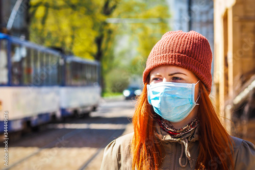 OLYMPUS DIGITBeautiful young European woman with ginger coloured hair on the street with a medical face mask on. Closeup of a young female in a respirator to protect against infection with coAL CAMERA