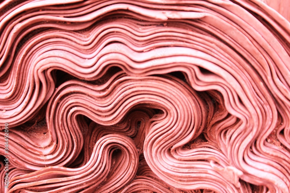 Abstract pink waves background. Roll of red fabric. Background for the website, page or phone. red roll of knitted fabric. Texture, background.