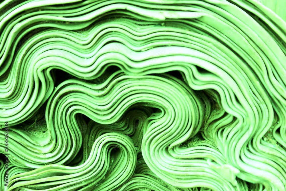 Abstract green waves background. Roll of green fabric. Background for the website, page or phone. Green roll of knitted fabric. Texture, background.