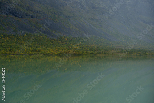 Reflection of misty mountain in Laddjujavri lake in rainy day in Sweden Lapland 