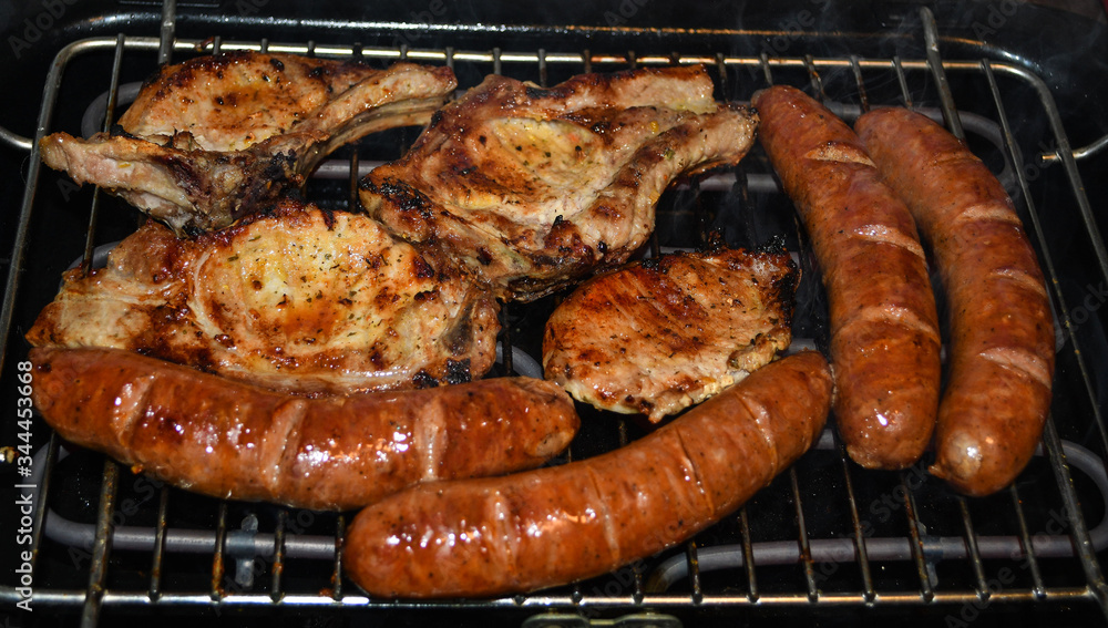 Pork pieces of meat and home-made sausages are grilled on barbeque