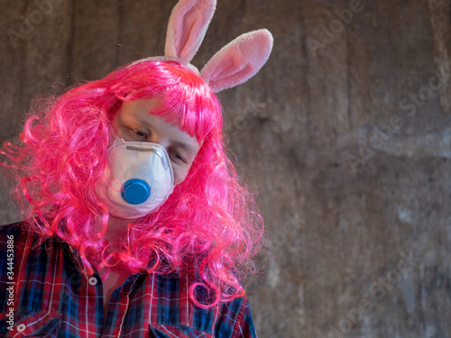 Fototapeta Naklejka Na Ścianę i Meble -  Attractive girl in pink wig and medical mask in plaid shirt, pink jacket and carnival ears of hare. Beautiful middle aged woman with cancer without hair