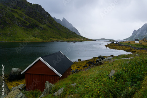 Lonely red hut on the shore of Reinefjorden in a rainy day in Lofoten islands of Norway 