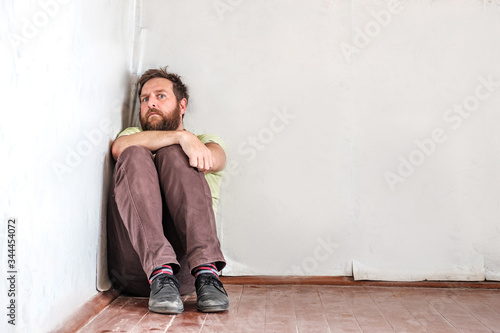 a man with a beard looks anxiously from the corner in which he has clogged