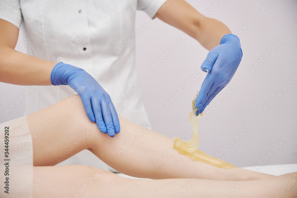 the procedure shugaring. a master in blue medical gloves removes sugar paste with a manual technique the procedure shugaring. a master in blue medical gloves removes sugar paste with a manual technique