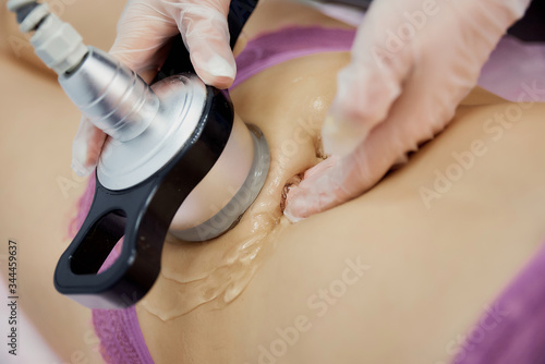 cavitation of the abdomen by a cosmetologist. The nozzle touches the skin