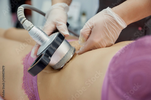 cavitation of the abdomen by a cosmetologist. The nozzle touches the skin