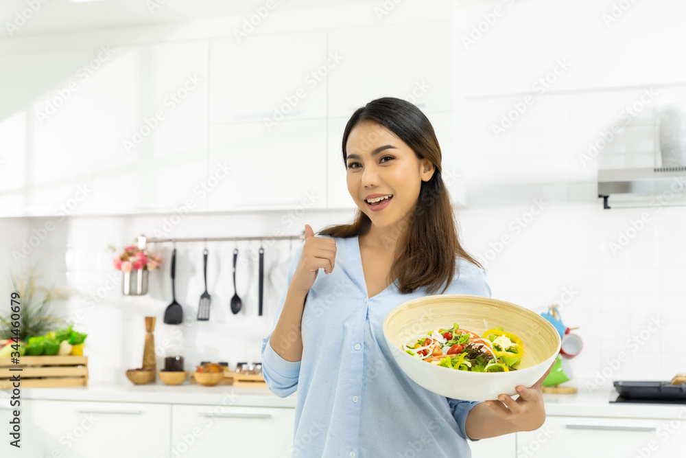 Young Woman Cooking in the kitchen. Healthy Food - Vegetable Salad Diet. Healthy Lifestyle. Cooking delicious food during the COVID-19 self-quarantine 14 days. Stay at home concept.