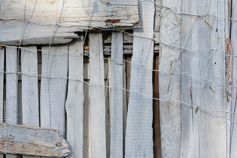 Fragment of an old fence. Texture of metal mesh and wooden boards