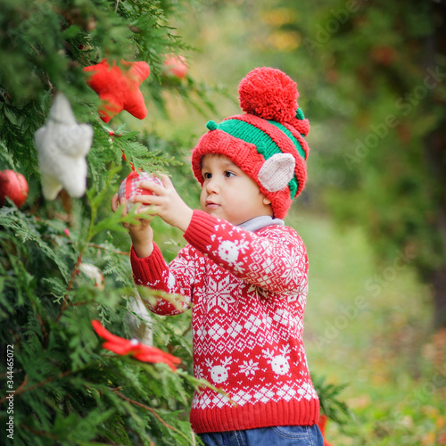 Child waiting for Christmas in wood. portrait of little boy near christmas tree. Baby decorating pine. winter holidays and people concept. Merry Christmas and Happy Holidays