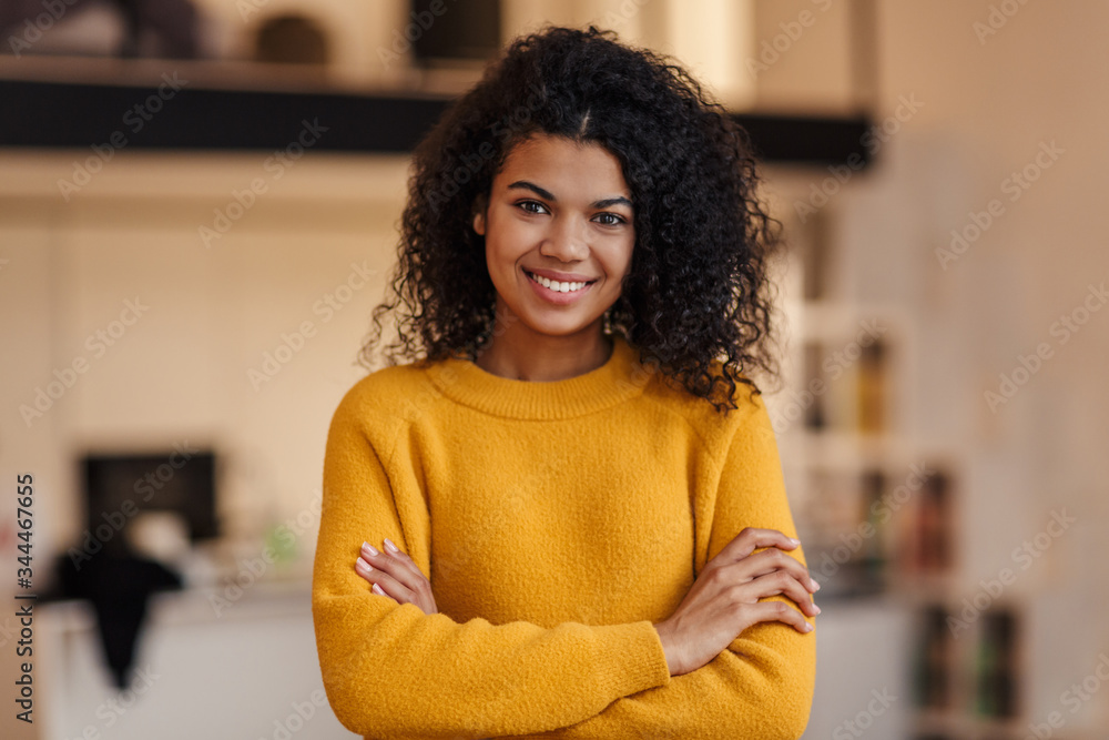 Image of pleased african american woman smiling and looking at camera Image of pleased african american woman smiling and looking at camera
