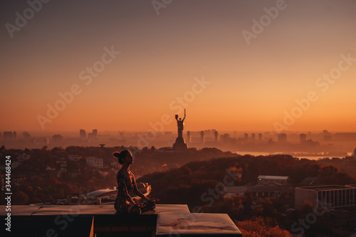 Woman doing yoga on the roof of a skyscraper in big city.