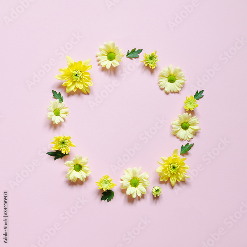 Wreath of yellow chrysanthemums on pink background with copy space.