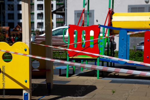 Indoor playgrounds during the coronavirus epidemic. A red ribbon is wrapped in a playground - a ban on visiting parks and public places during a pandemic. Children's houses and slides on the street.