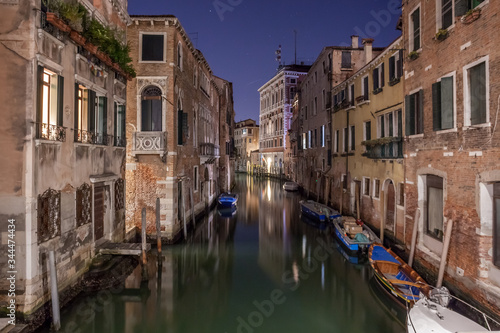 Narrow canal with boats and vintage houses at dusk. Venice city at night © k_samurkas