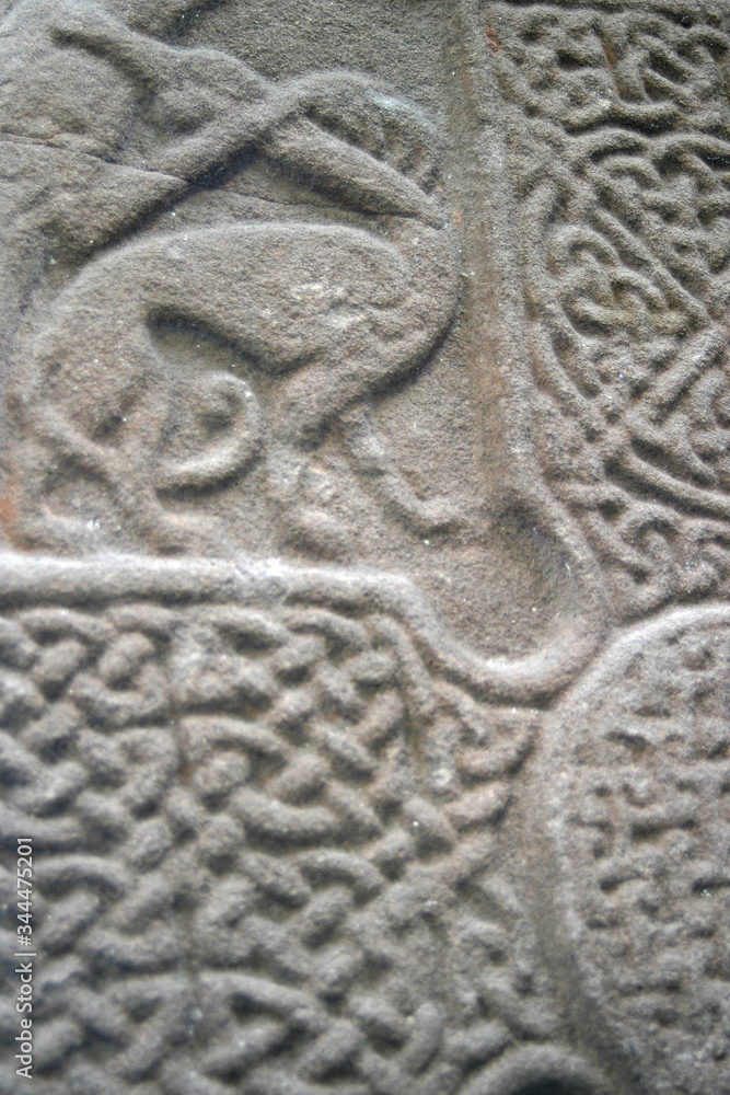 Ancient abstract design carved onto a standing stone in northern europe. Shows animal possiblybeing hunted beside a celic cross Ancient abstract design carved onto a standing stone in northern europe. Shows animal possiblybeing hunted beside a celic cross