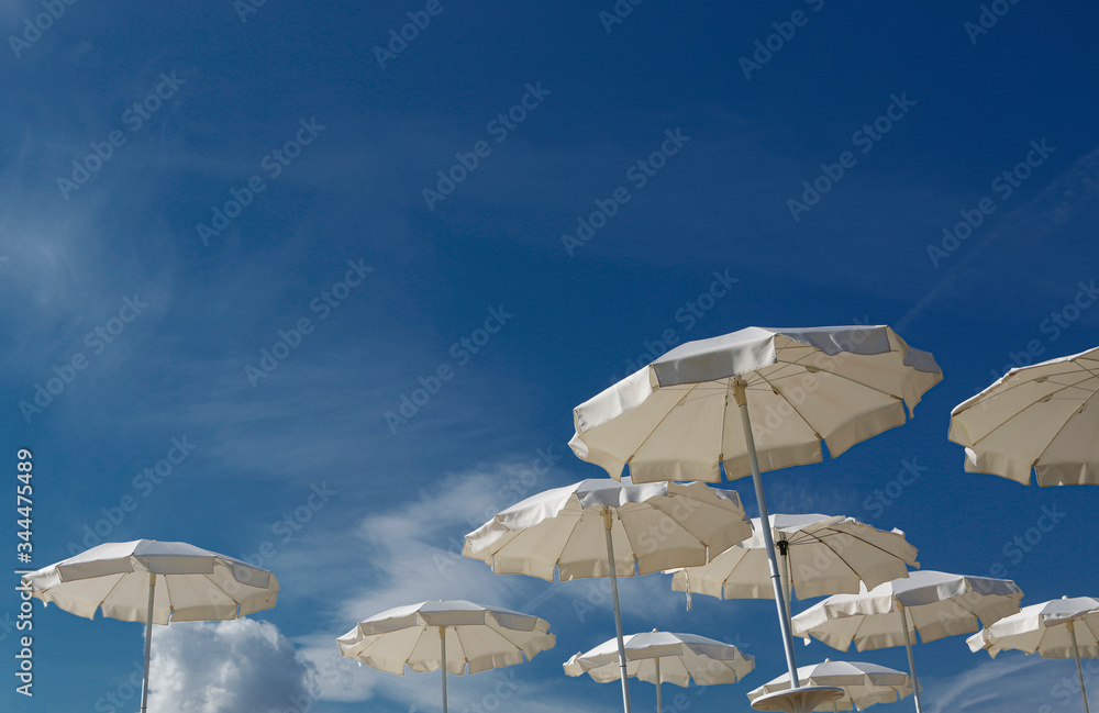 ombrelloni bianchi in sequenza sparsa,  su cielo blu