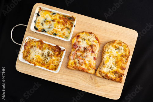 Pizza cheese toasted bread with ham cheese and imitation crab on wooden cutting boards. Isolate on black 