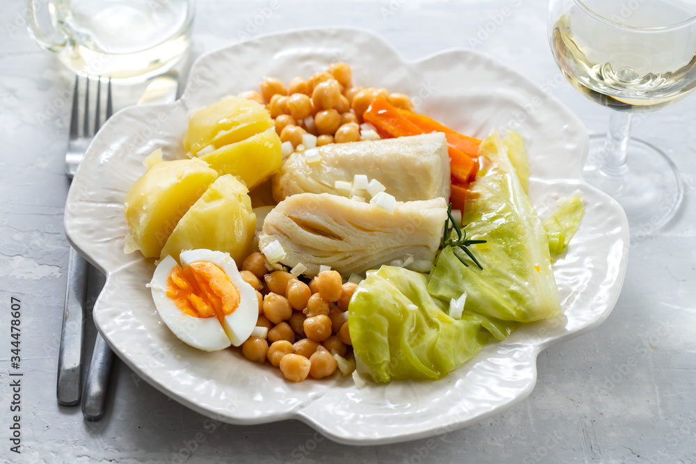 boiled cod fish with boiled vegetables and egg on white dish and glass of wine on ceramic background boiled cod fish with boiled vegetables and egg on white dish and glass of wine on ceramic background