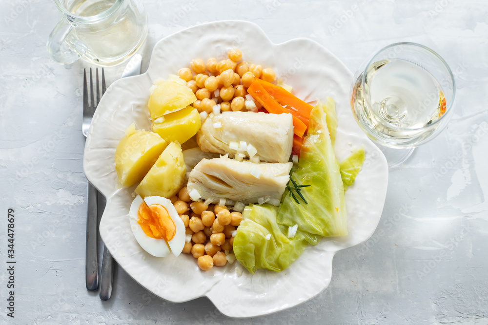 boiled cod fish with boiled vegetables and egg on white dish and glass of wine on ceramic background boiled cod fish with boiled vegetables and egg on white dish and glass of wine on ceramic background