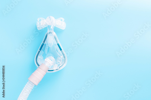 CPAP mask on blue background with copy space. Sleep apnea treatment concept. 