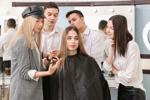 Professional hairdresser teaching young people in salon