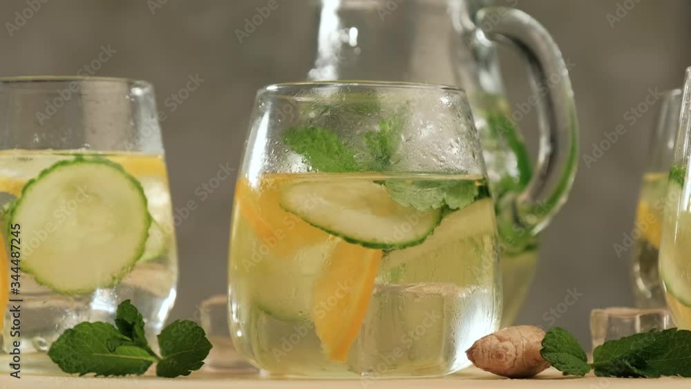 Rotating of glasses with summer healthy lemonade, cocktails of citrus infused water or mojitos, with lime lemon orange, ice and mint, diet detox beverages, on gray background. Rotating of glasses with summer healthy lemonade, cocktails of citrus infused water or mojitos, with lime lemon orange, ice and mint, diet detox beverages, on gray background.