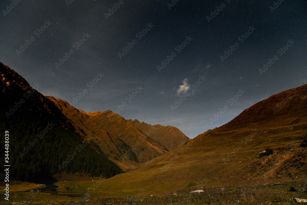 The Tusheti Mountains at night under a starry sky with a moving cloud