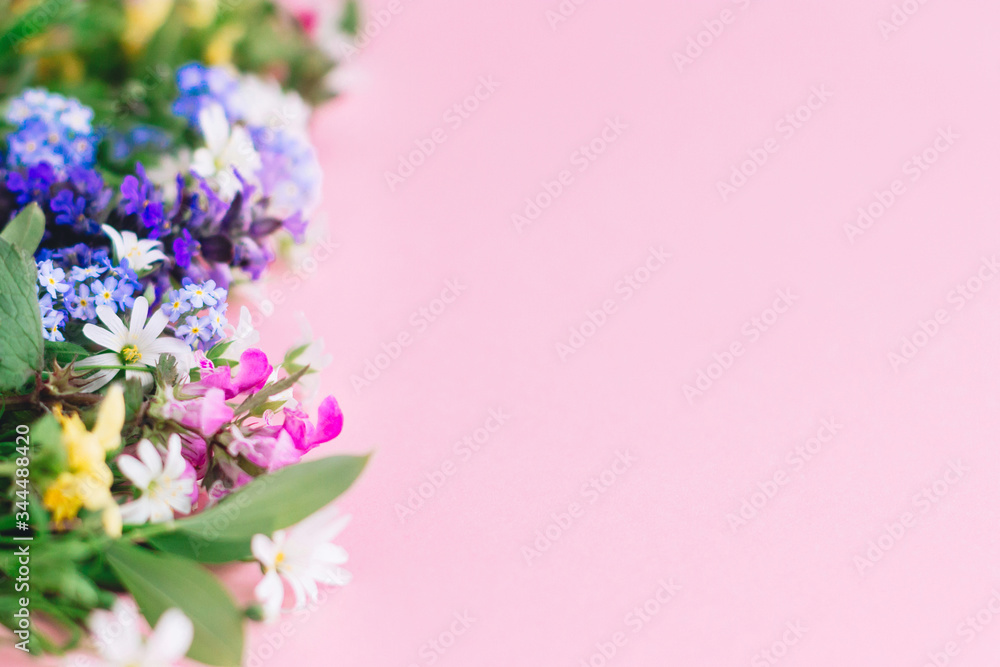 Colorful spring wildflowers border on pink paper background, space for text. Floral greeting card template. Happy Mother's day concept. Hello spring. Blooming spring flowers