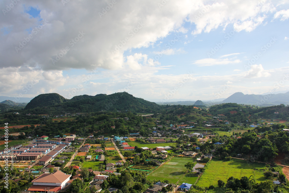 View of a small village, vegetation and green mountains from above the Big Buddha of Chiang Rai