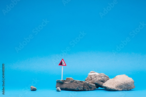 A stone next to a cliff sign, on blue background.