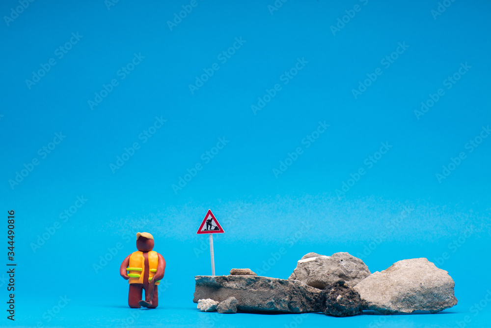 A plasticine man next to a bunch of rocks, on blue background. A plasticine man next to a bunch of rocks, on blue background.