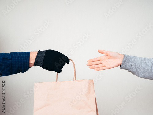 Two hands with a paper bag on a white background. Delivery concept for the COVID-19 pandemic.