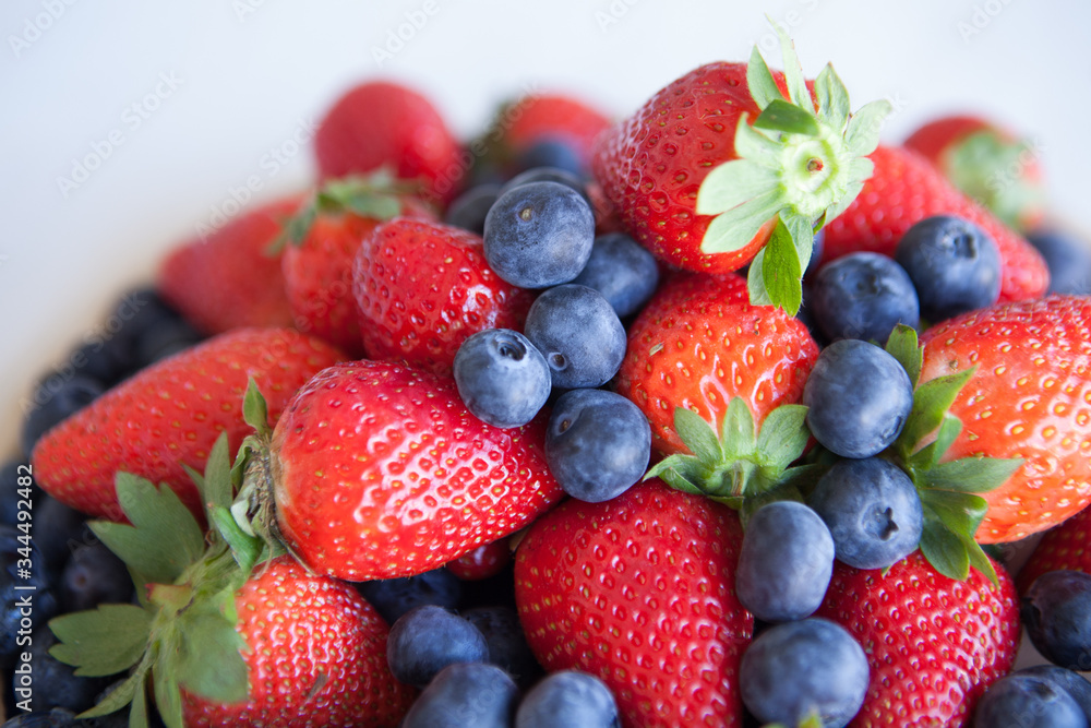 Blueberries and strawberries in a ceramic plate on the table. Natural light. Blueberries and strawberries in a ceramic plate on the table. Natural light.