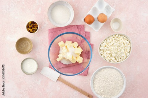 flour, cottage cheese in bowl and milk, eggs. products for making cheesecakes on a pink backround.